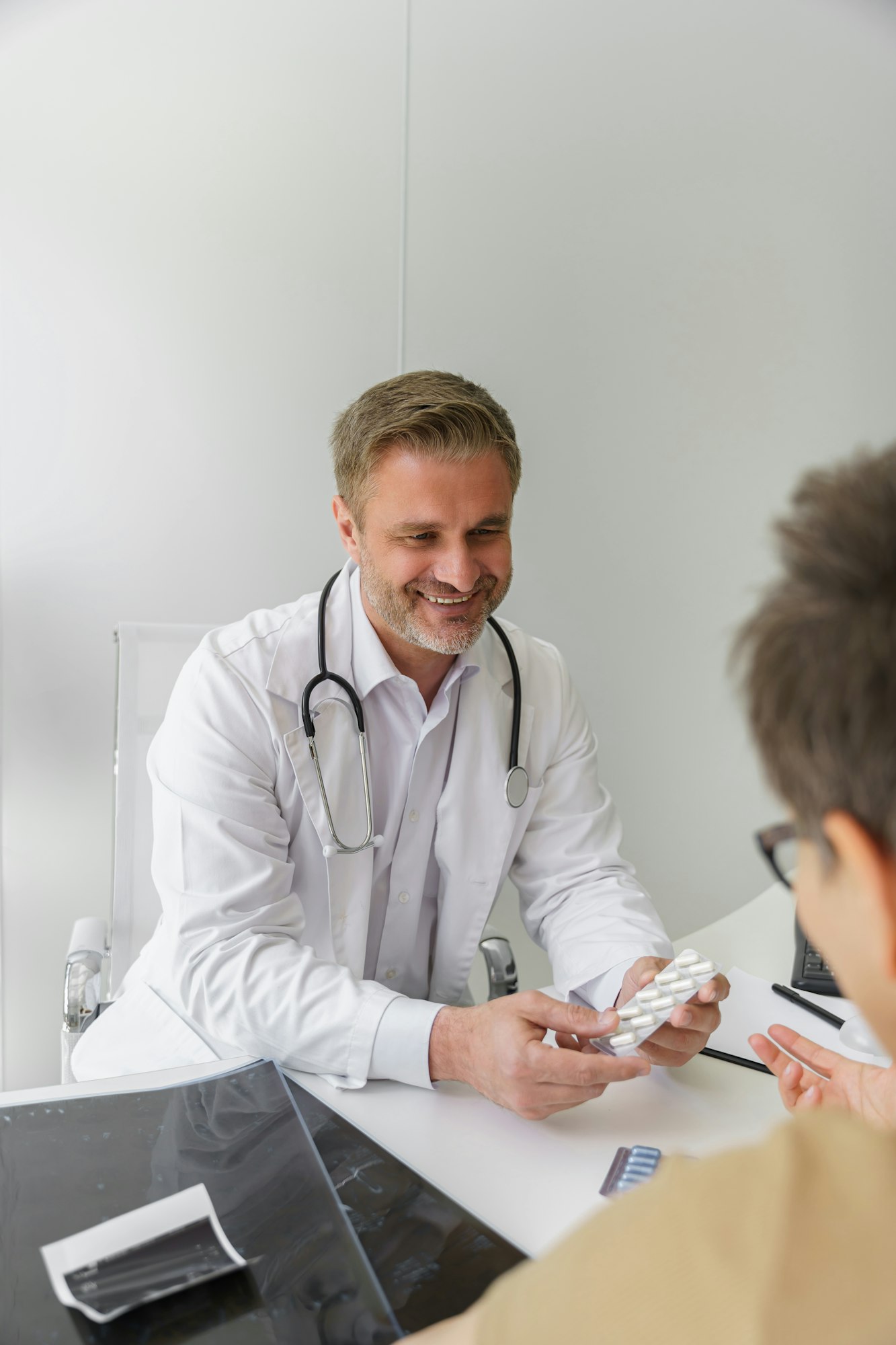 Close up of smiling doctor prescribing pills to female patient during appointment in his office